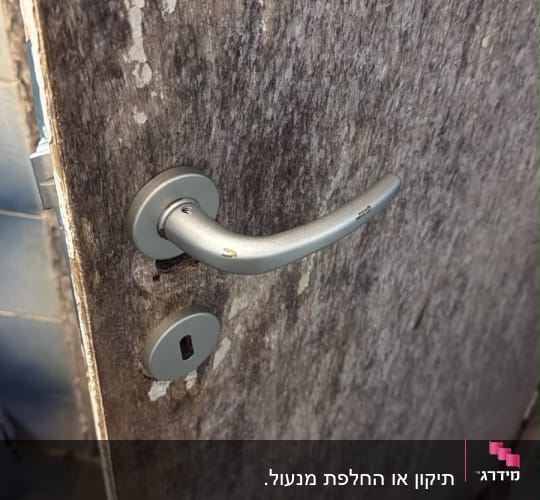 ידית מתכת כסופה ומנעול מותקנים על דלת עץ